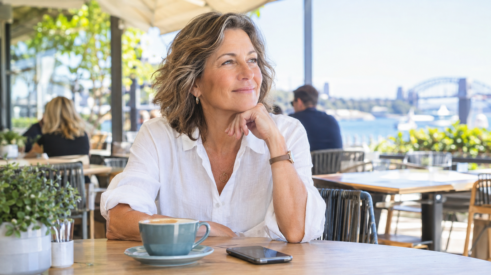 Confident woman in her fifties in a bright public cafe with her phone on the table